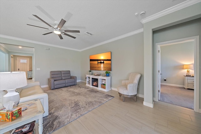 living room featuring baseboards, visible vents, ceiling fan, a lit fireplace, and crown molding