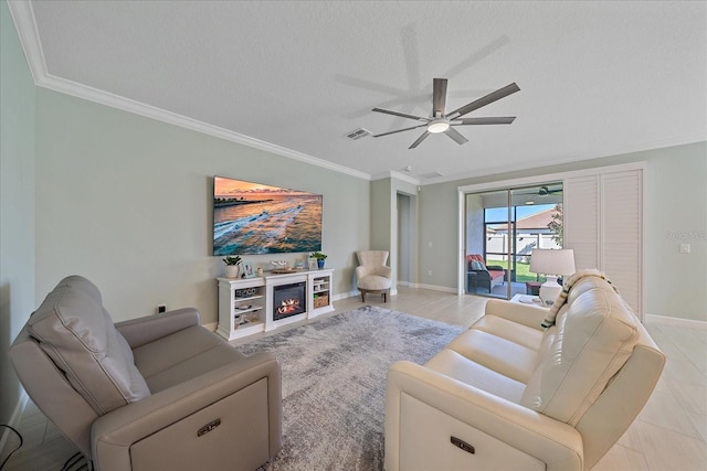 living area featuring a ceiling fan, visible vents, a lit fireplace, a textured ceiling, and crown molding