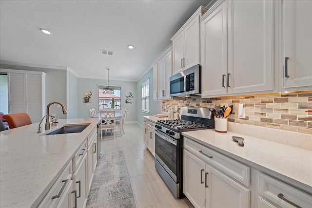 kitchen featuring visible vents, a sink, decorative backsplash, stainless steel appliances, and white cabinets