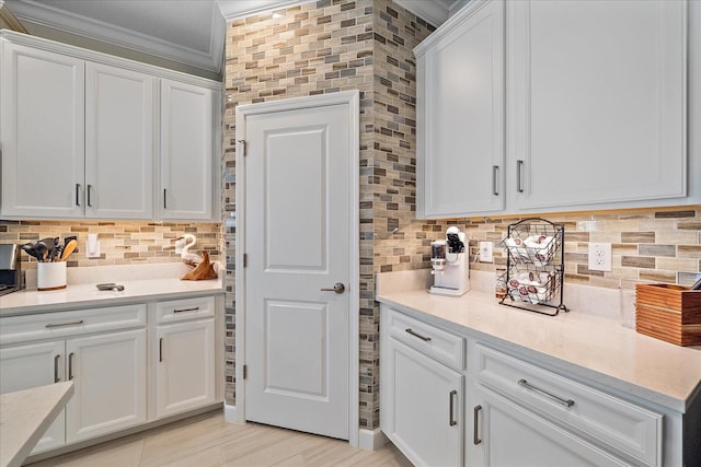 kitchen featuring white cabinetry, tasteful backsplash, crown molding, and light countertops