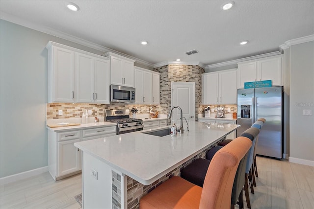 kitchen with visible vents, backsplash, ornamental molding, appliances with stainless steel finishes, and white cabinetry