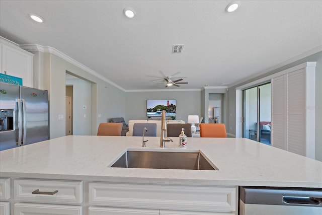 kitchen featuring a sink, stainless steel appliances, open floor plan, and ornamental molding