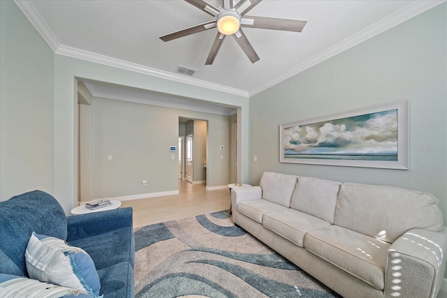 living area featuring visible vents, wood finished floors, crown molding, baseboards, and ceiling fan