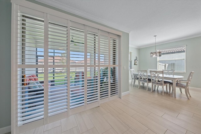 dining room featuring a textured ceiling, crown molding, baseboards, and wood finished floors