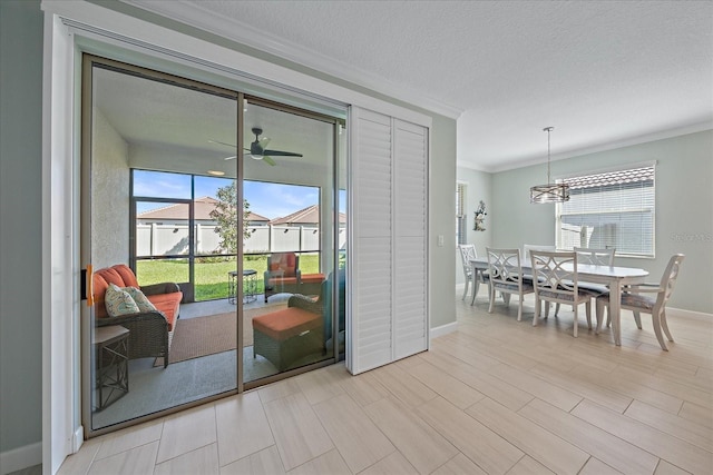 doorway to outside with a wealth of natural light, a textured ceiling, crown molding, and a ceiling fan