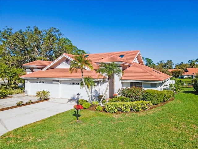 mediterranean / spanish house with a front yard, stucco siding, concrete driveway, a garage, and a tile roof