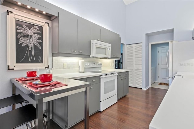 kitchen featuring white appliances, dark wood-style floors, gray cabinetry, light countertops, and backsplash