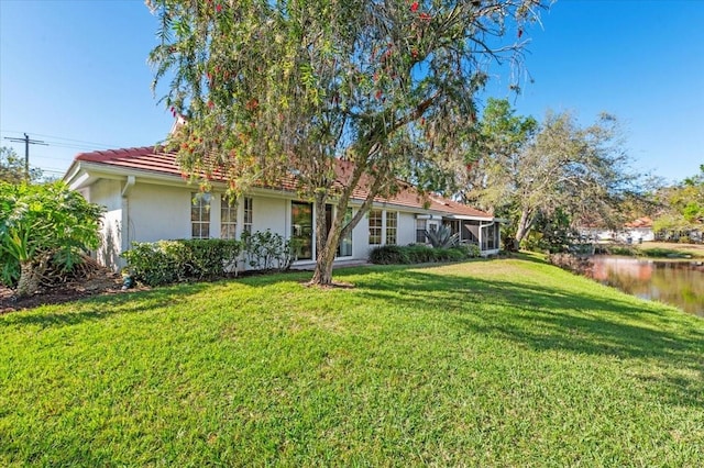 view of front of house with stucco siding, a tile roof, and a front lawn