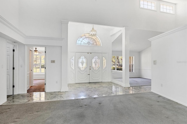 foyer entrance featuring marble finish floor, ceiling fan with notable chandelier, carpet, baseboards, and a towering ceiling