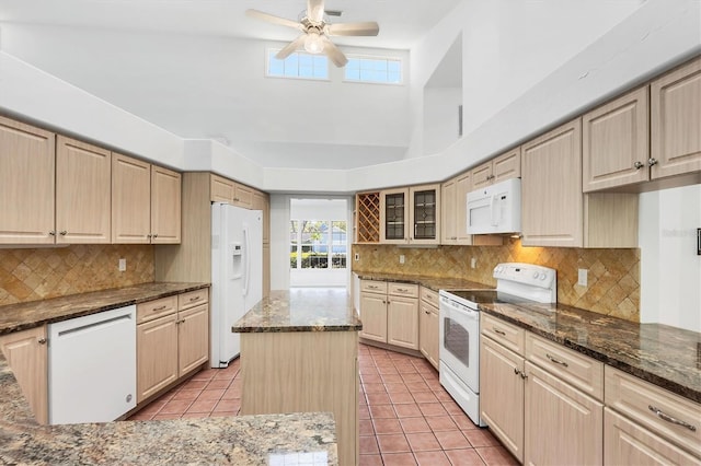 kitchen featuring glass insert cabinets, dark stone counters, light tile patterned flooring, white appliances, and a ceiling fan