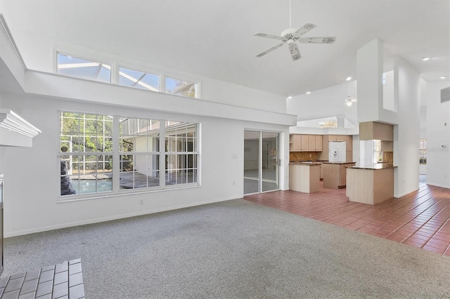 unfurnished living room with high vaulted ceiling, light tile patterned flooring, baseboards, light colored carpet, and ceiling fan