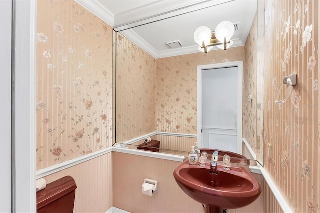 bathroom with ornamental molding, wainscoting, and wallpapered walls