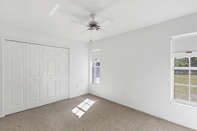 unfurnished bedroom featuring carpet, baseboards, a closet, and ceiling fan