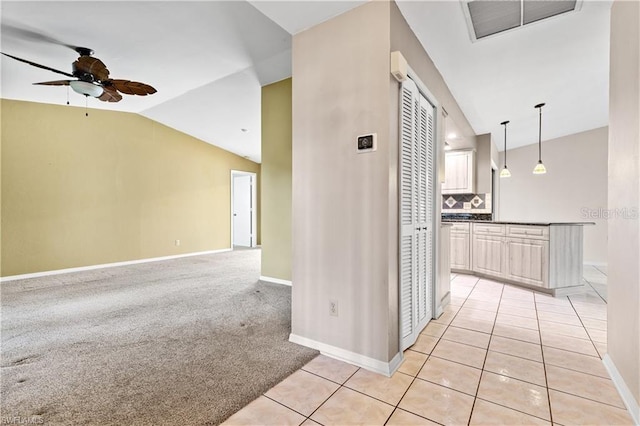 hall with light tile patterned floors, visible vents, vaulted ceiling, and baseboards