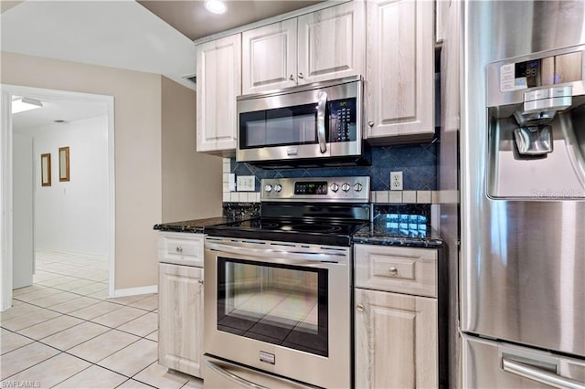 kitchen featuring dark stone counters, tasteful backsplash, appliances with stainless steel finishes, baseboards, and light tile patterned flooring