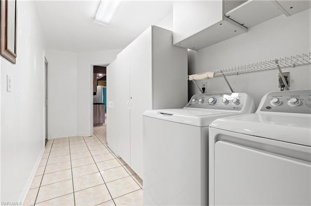 laundry area featuring baseboards, light tile patterned floors, laundry area, and washing machine and dryer