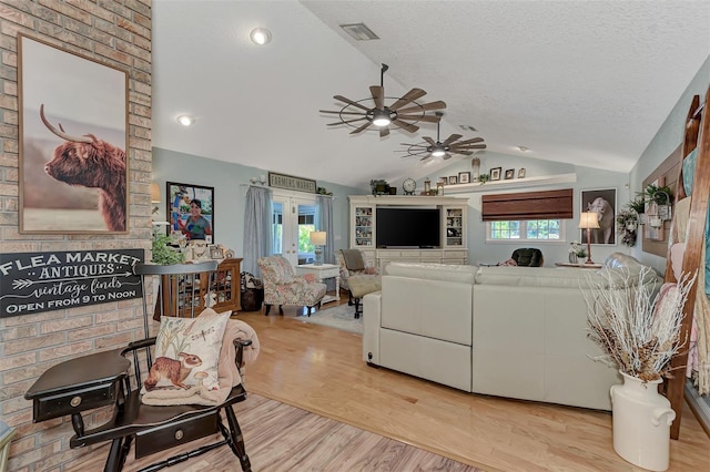 living room with visible vents, lofted ceiling, a textured ceiling, and wood finished floors