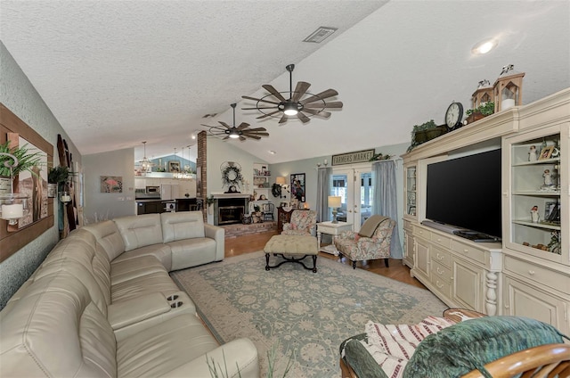 living area featuring visible vents, lofted ceiling, light wood-style floors, french doors, and a textured ceiling