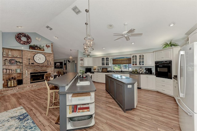 kitchen featuring light wood finished floors, dark countertops, a center island, a fireplace, and black appliances