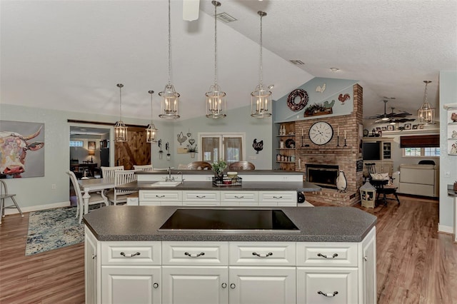 kitchen with dark countertops, black electric cooktop, open floor plan, and a spacious island