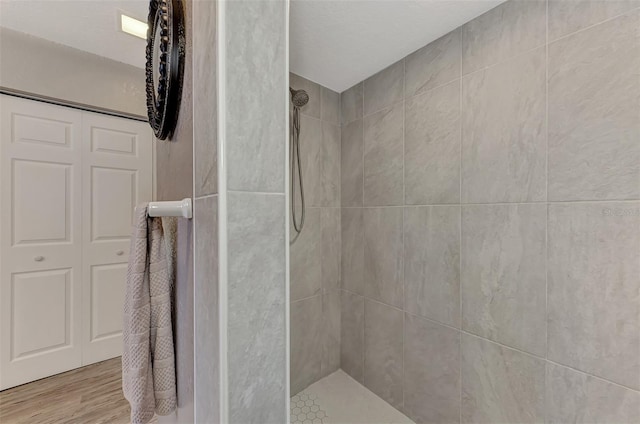 full bathroom featuring tiled shower and wood finished floors