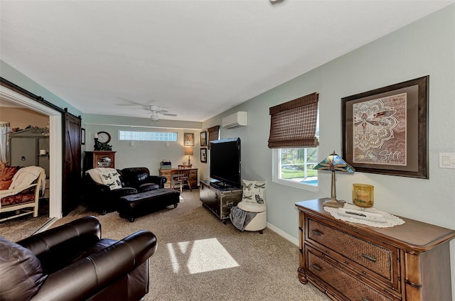 living area with baseboards, ceiling fan, light colored carpet, a barn door, and a wall unit AC