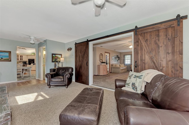 living area featuring a barn door, carpet, and ceiling fan