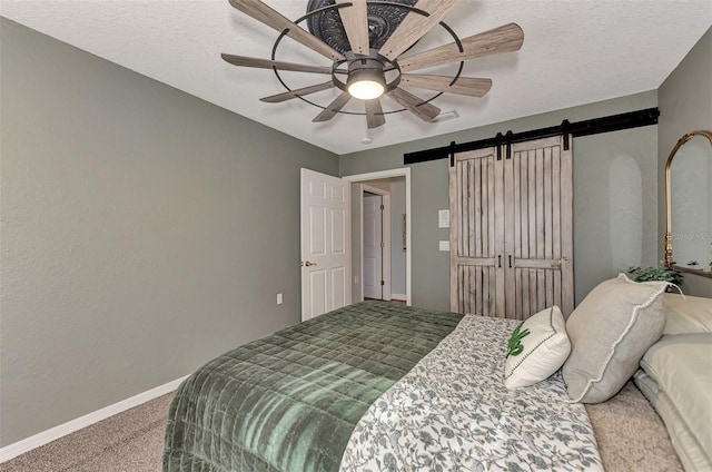 carpeted bedroom featuring a barn door, baseboards, a textured ceiling, and ceiling fan