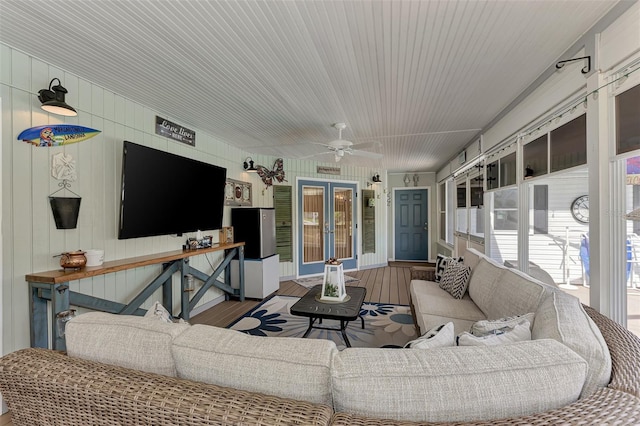 living room with a ceiling fan, a sunroom, wood finished floors, and french doors