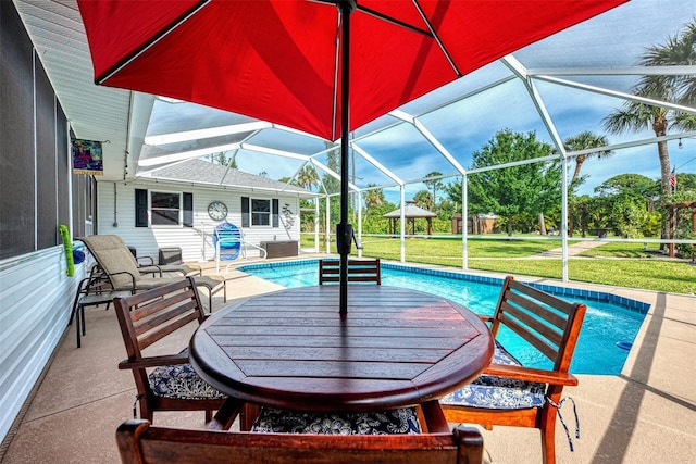 pool with a patio area, glass enclosure, and a yard