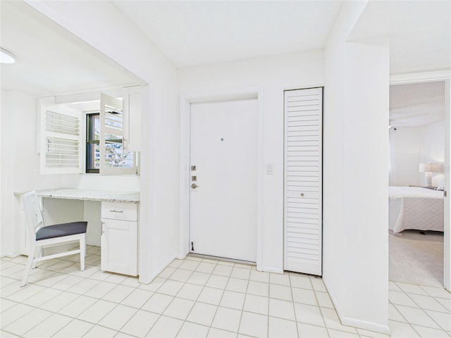 foyer entrance with light tile patterned floors and built in study area