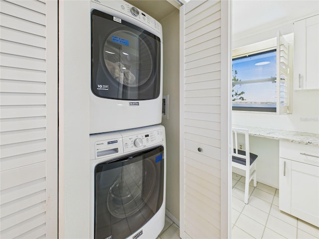 laundry area with laundry area, stacked washer and dryer, and light tile patterned floors