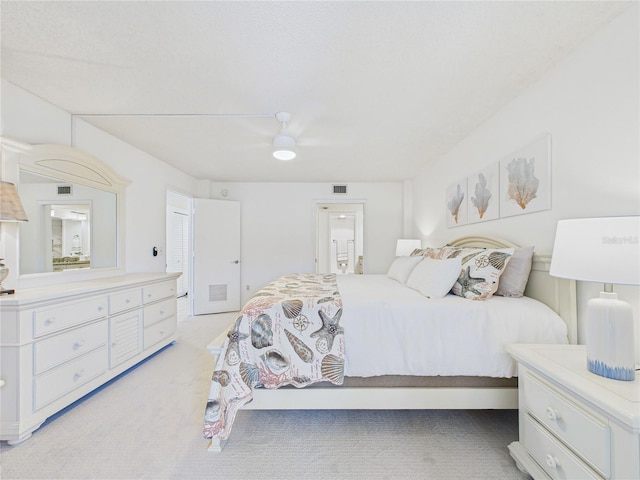 bedroom featuring visible vents, light colored carpet, ensuite bath, and ceiling fan