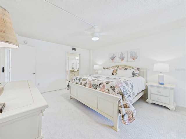 bedroom featuring light carpet, visible vents, a textured ceiling, and ceiling fan