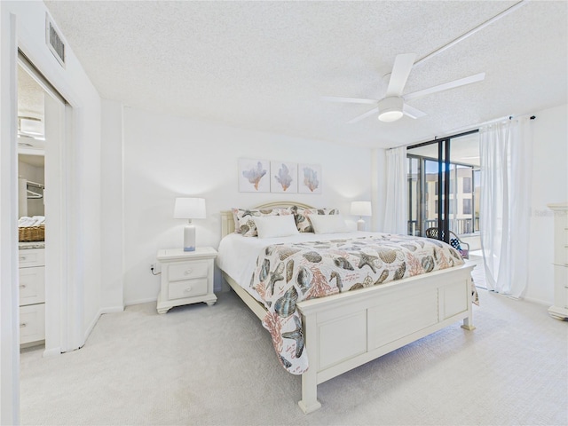 bedroom featuring visible vents, light colored carpet, access to exterior, and a textured ceiling