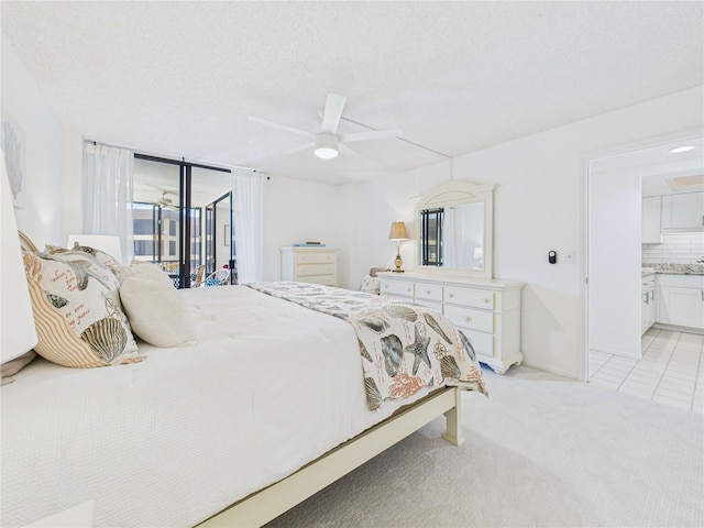 bedroom featuring light carpet, ensuite bath, a textured ceiling, a ceiling fan, and access to outside