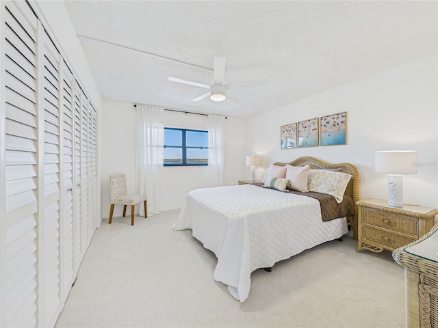 bedroom with light colored carpet, a ceiling fan, and a textured ceiling