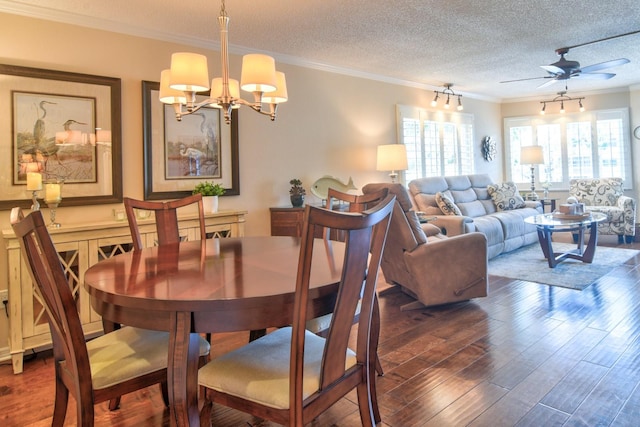 dining space featuring a textured ceiling, ceiling fan with notable chandelier, wood finished floors, and ornamental molding