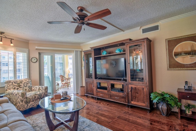 living area with a ceiling fan, visible vents, dark wood-style flooring, ornamental molding, and a textured ceiling