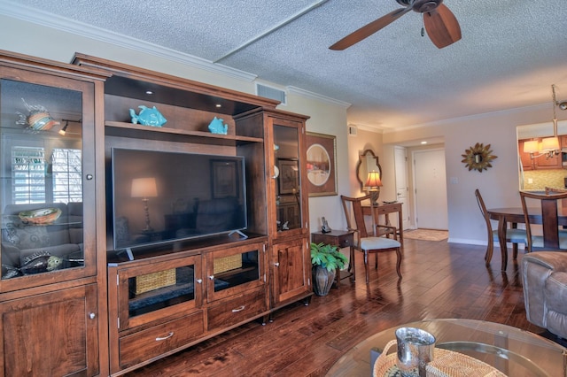 living room with a ceiling fan, visible vents, dark wood-style flooring, ornamental molding, and a textured ceiling