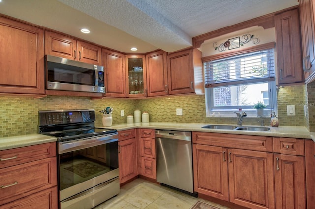 kitchen with a sink, brown cabinets, appliances with stainless steel finishes, and light countertops