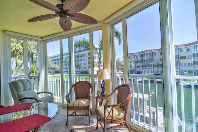 sunroom / solarium with a ceiling fan and a water view