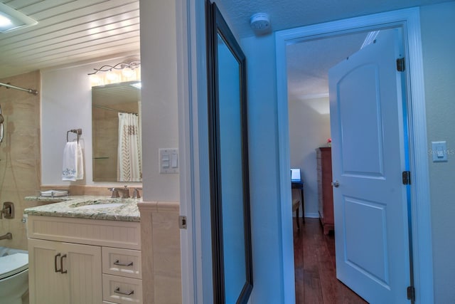 bathroom featuring curtained shower, toilet, vanity, and wood finished floors