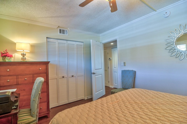 bedroom featuring visible vents, ornamental molding, a textured ceiling, a closet, and ceiling fan