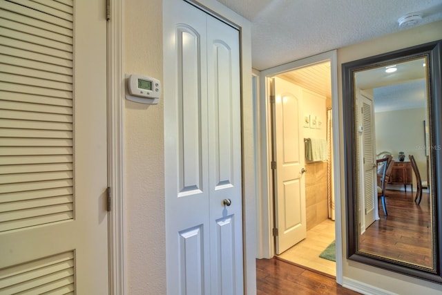 corridor with a textured ceiling and dark wood finished floors