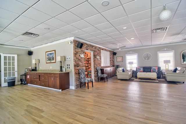 living area with visible vents, light wood-style flooring, and ornamental molding