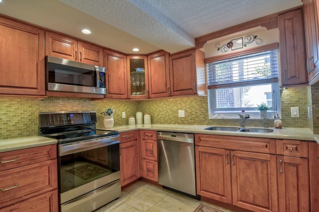 1250 N Portofino Dr Unit 201, Sarasota, FL 34242 - kitchen featuring stainless steel appliances, a sink, a textured ceiling, brown cabinets, and light countertops