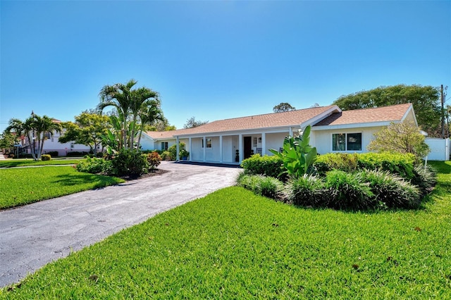 ranch-style home with stucco siding, a front lawn, and driveway