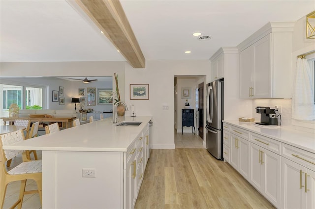 kitchen with a sink, a peninsula, appliances with stainless steel finishes, a breakfast bar area, and light countertops