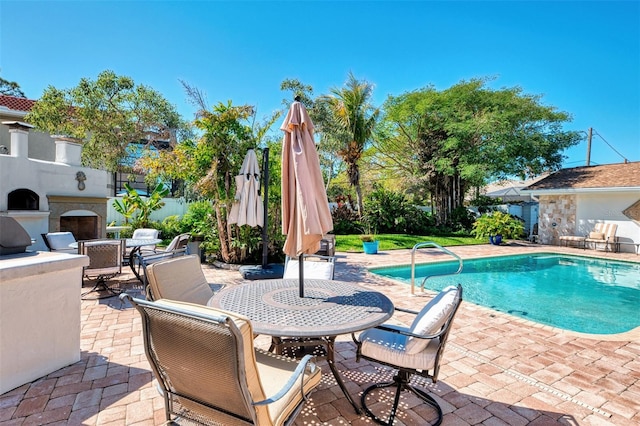 view of swimming pool with a fenced in pool, fence, outdoor dining area, an outdoor fireplace, and a patio